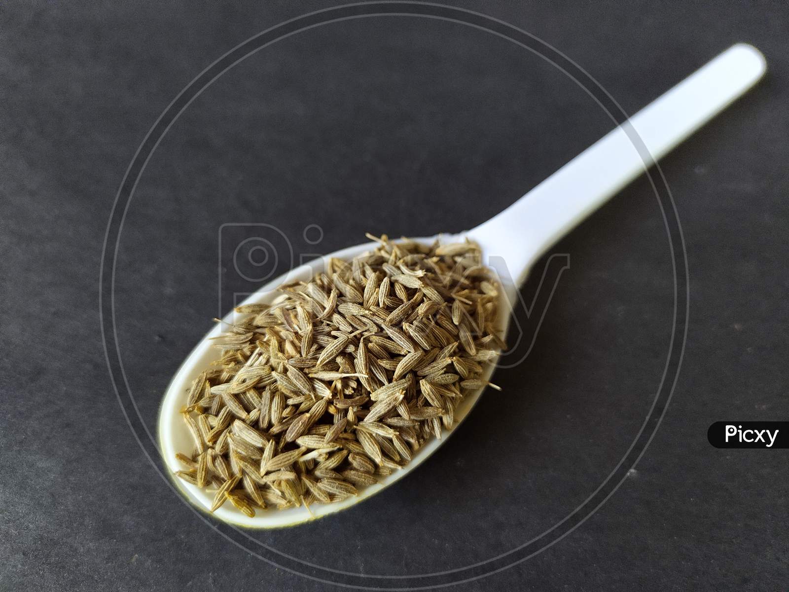 White cumin seeds in a spoon.