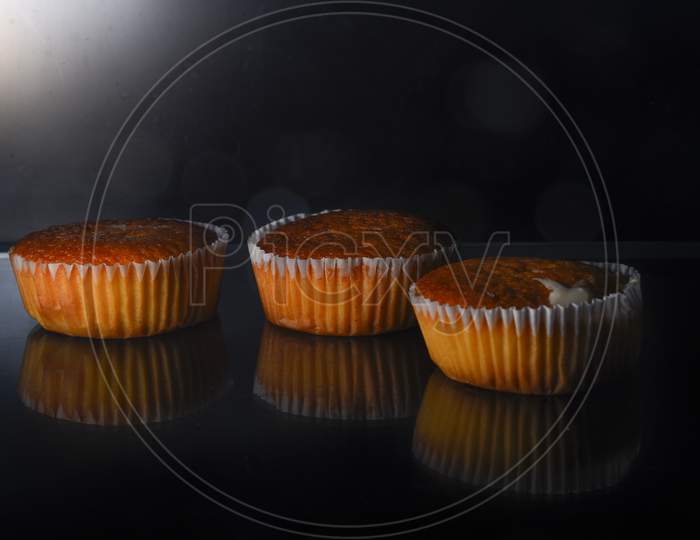 Fresh tasty cupcake on dark background.Beautiful delicious red velvet capkake with a creamy cream cap on a shale stone stand against a black background