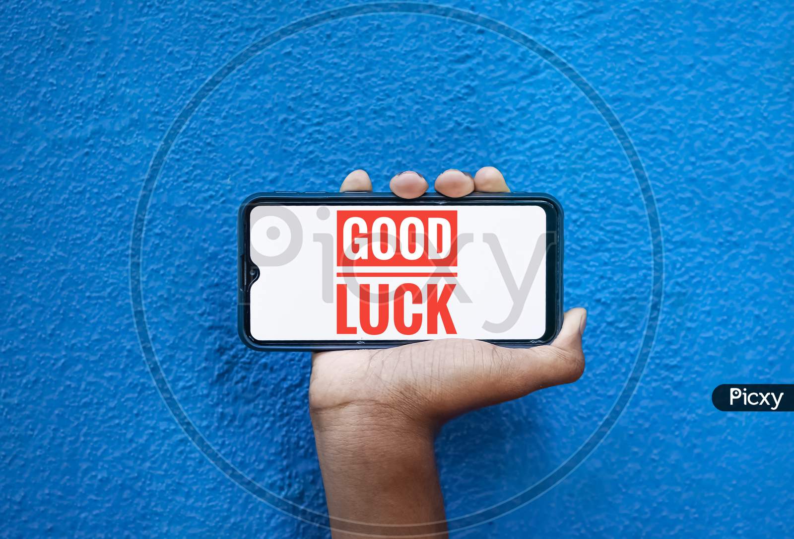 Good Luck Wording On Smart Phone Screen Isolated On Blue Background With Copy Space For Text. Person Holding Mobile On His Hand And Showing Front Of The Screen Word Good Luck
