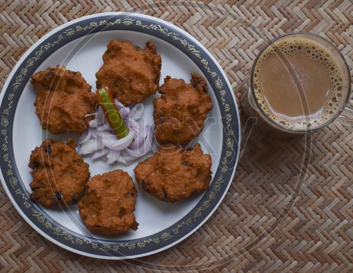 Top View Of Dal Vada, Masala Vada, Chana Vada Served With Cut Onion And Green Chilly And Tea On Serving Mat. Deep Fried Indian Cuisine Snacks, Lentils, Pulses Fritters