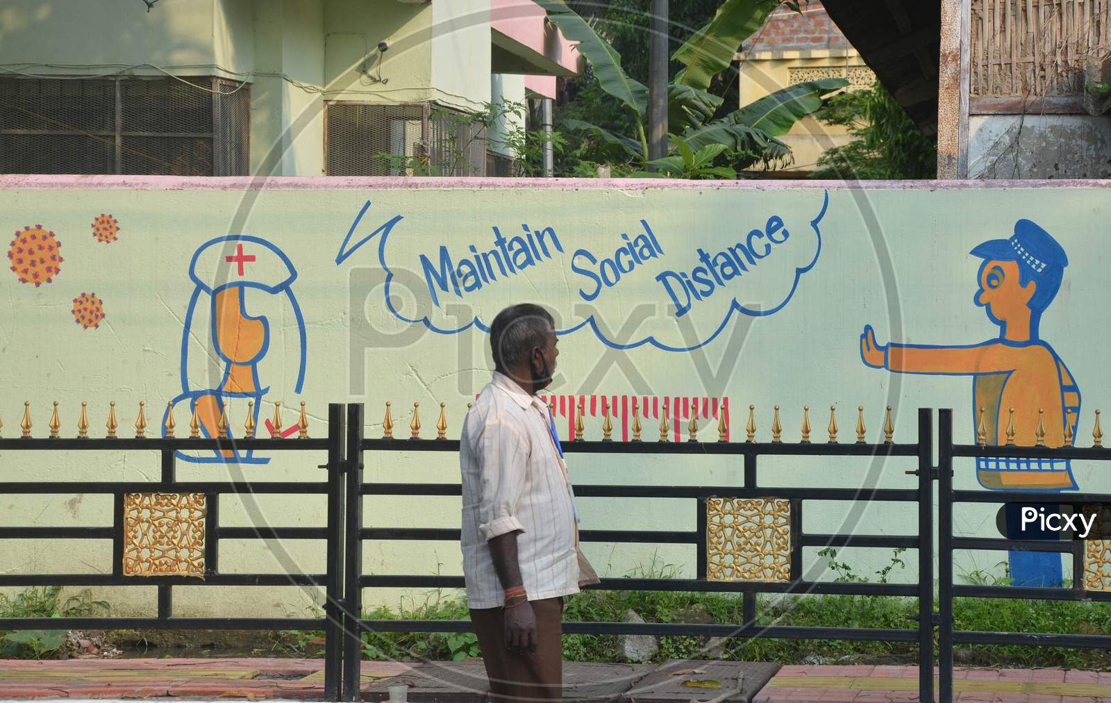 A man Wearing A Face Mask Walks Past A Mural During Nationwide Lockdown Amidst Coronavirus or COVID-19 Pandemic  In Guwahati District Of Assam,India