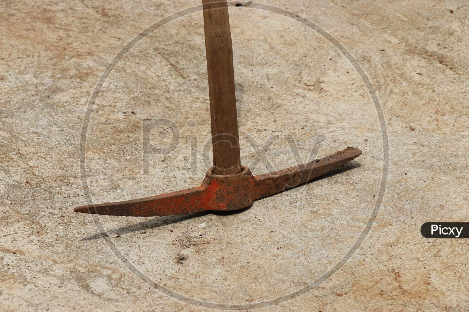 Pickaxe Which Is Old And Rusty With Wooden Handle Kept In Concrete Floor