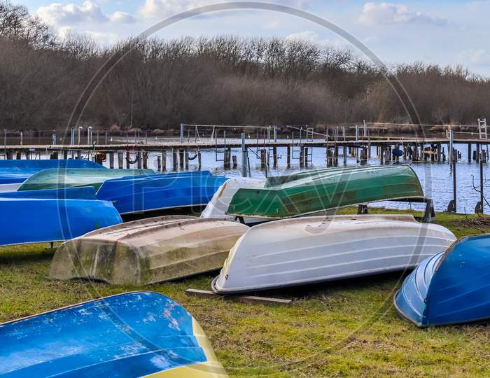 Multiple rowboats lying on a lawn at a beautiful lake on a sunny day