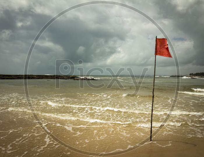 Beach With A Red Flag During A Storm. Desolate Beach With Crystal Clear Waters.