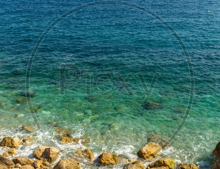Beautiful View Of The Cliff Submerging Under The Crystal Clear Waters Of The Mediterranean Sea.