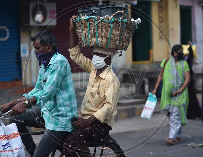A Man Carries A Basket Over His Head As He Rides Pillion On A Bicycle While Returning Home From A Market During The Nationwide Lockdown Amid Coronavirus Pandemic In Vijayawada.