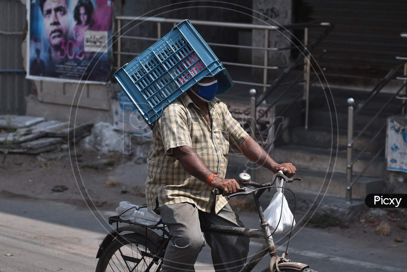 A Man Carries A Basket Over His Head As He Rides A Bicycle While Returning Home From A Market During The Nationwide Lockdown Amid Coronavirus Pandemic In Vijayawada.