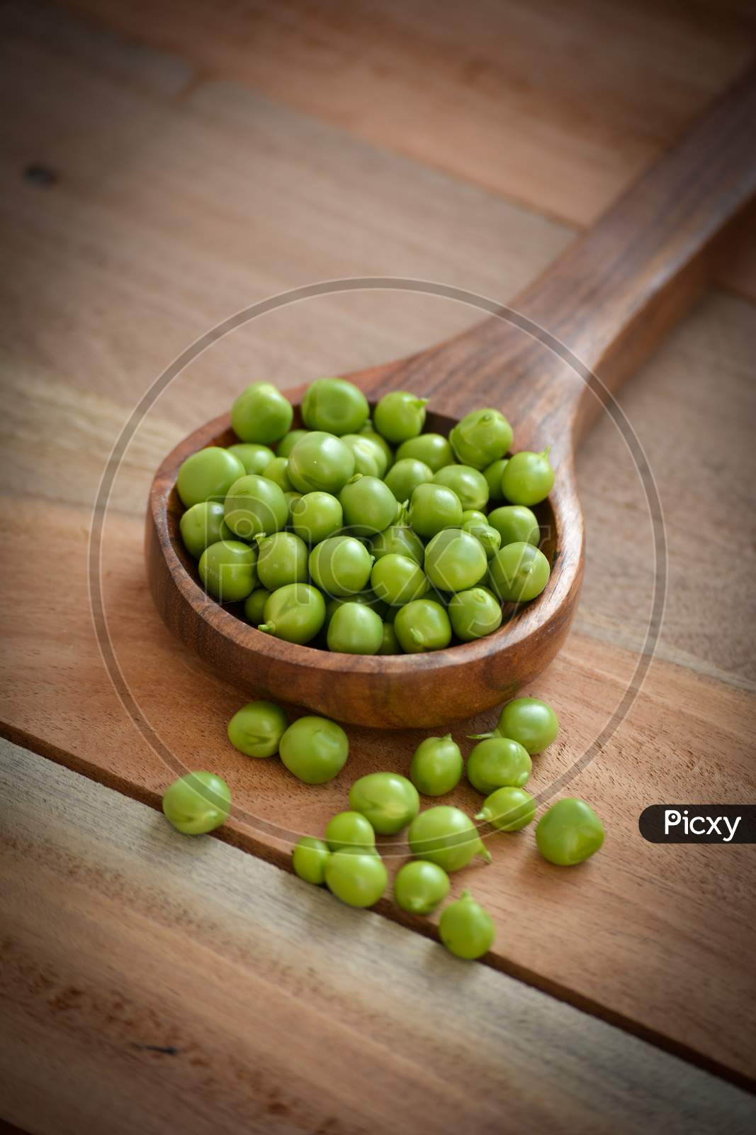 Fresh green peas in the wooden spoon