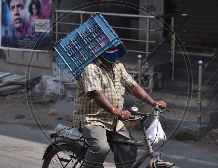 A Man Carries A Basket Over His Head As He Rides A Bicycle While Returning Home From A Market During The Nationwide Lockdown Amid Coronavirus Pandemic In Vijayawada.