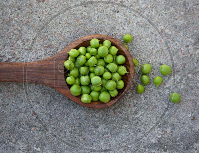 Fresh green peas in the wooden spoon