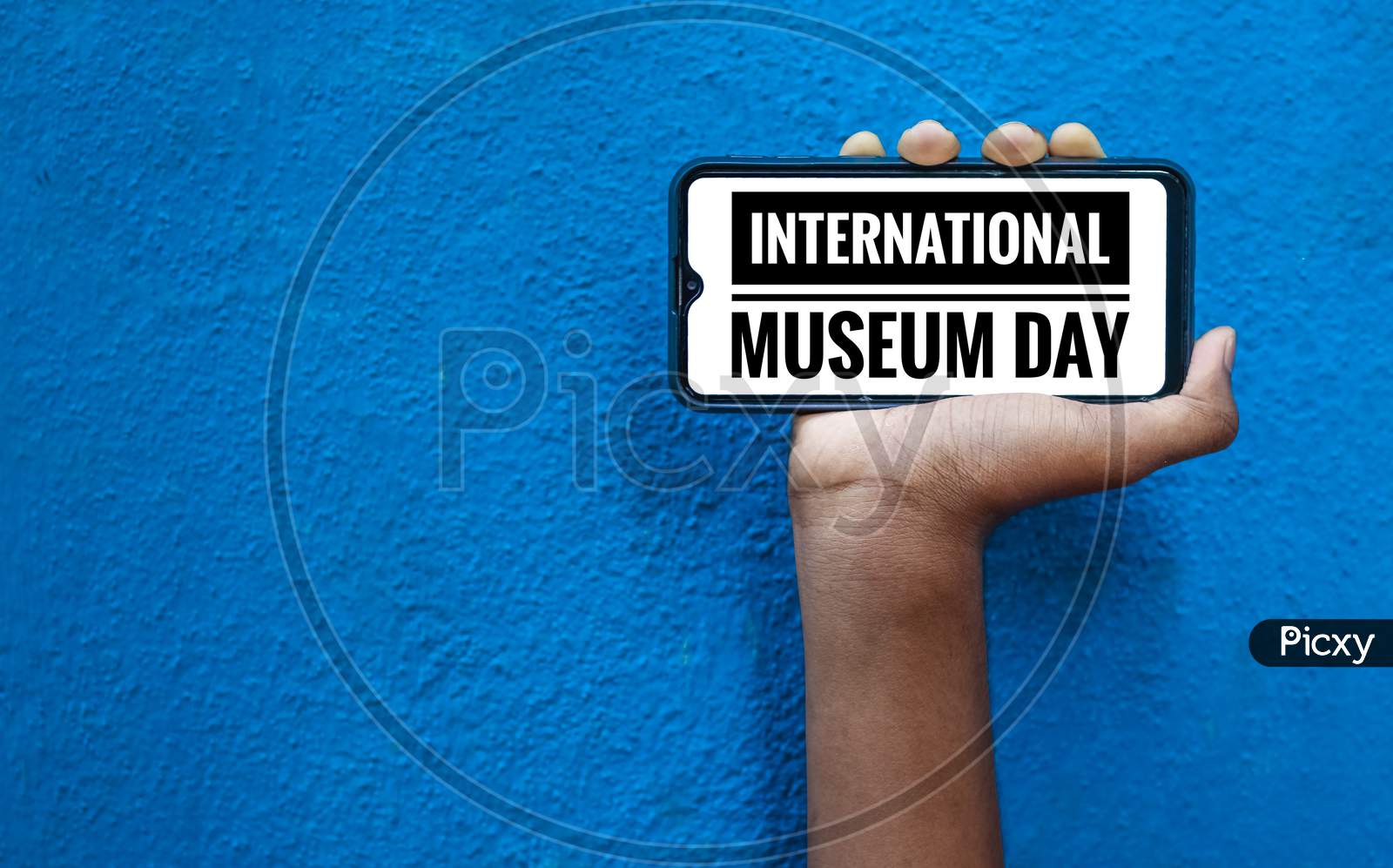 18 May - International Museum Day Word On Mobile Smart Phone Screen With Isolated On Blue Background. International Museum Day With Space For Text.