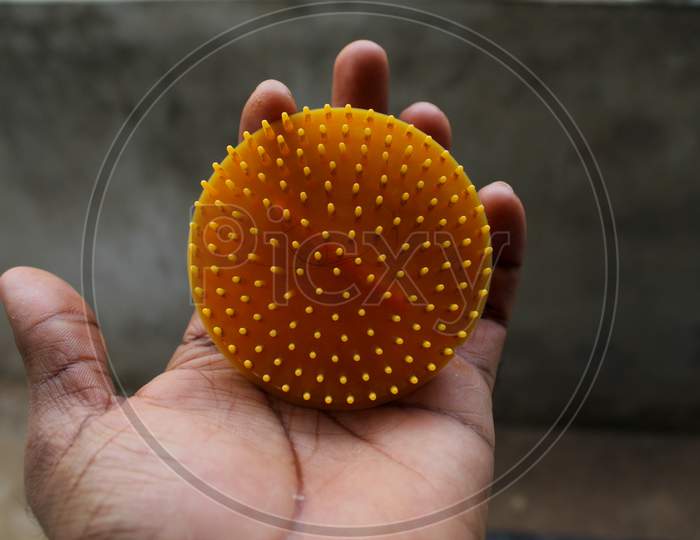 Yellow Round Hair Comb Held In Hand. It Is A Tool Used To Straighten Hair.