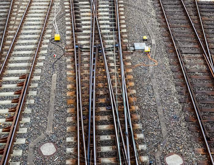 Railroad tracks and signs with junctions at a railway station in a perspective view