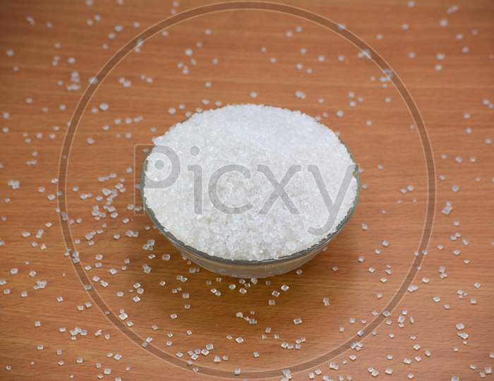Sugar in glass bowl on wooden background