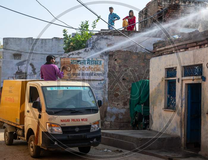 people watching A man on Nagar palika municipality vehicle sprays Disinfectants amid concerns over coronavirus or covid 19