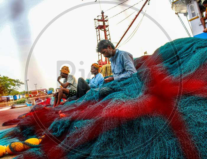 fisherman working on nets in fishery port old mangalore port