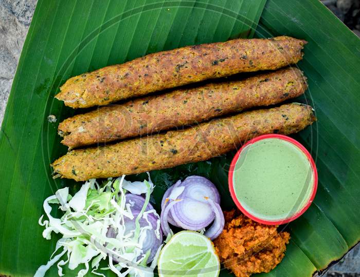 Seekh kebab on and chicken pieces on banana leaf, top view