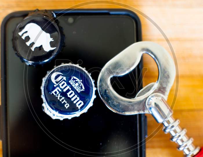 Mobile Phone On A Wooden Board With Beer Bottle Caps And An Opener Showing Online App For Alcohol Home Delivery.