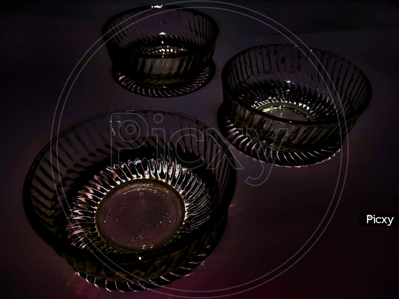 Three elegant charming glass bowls exposed and isolated in dark background.