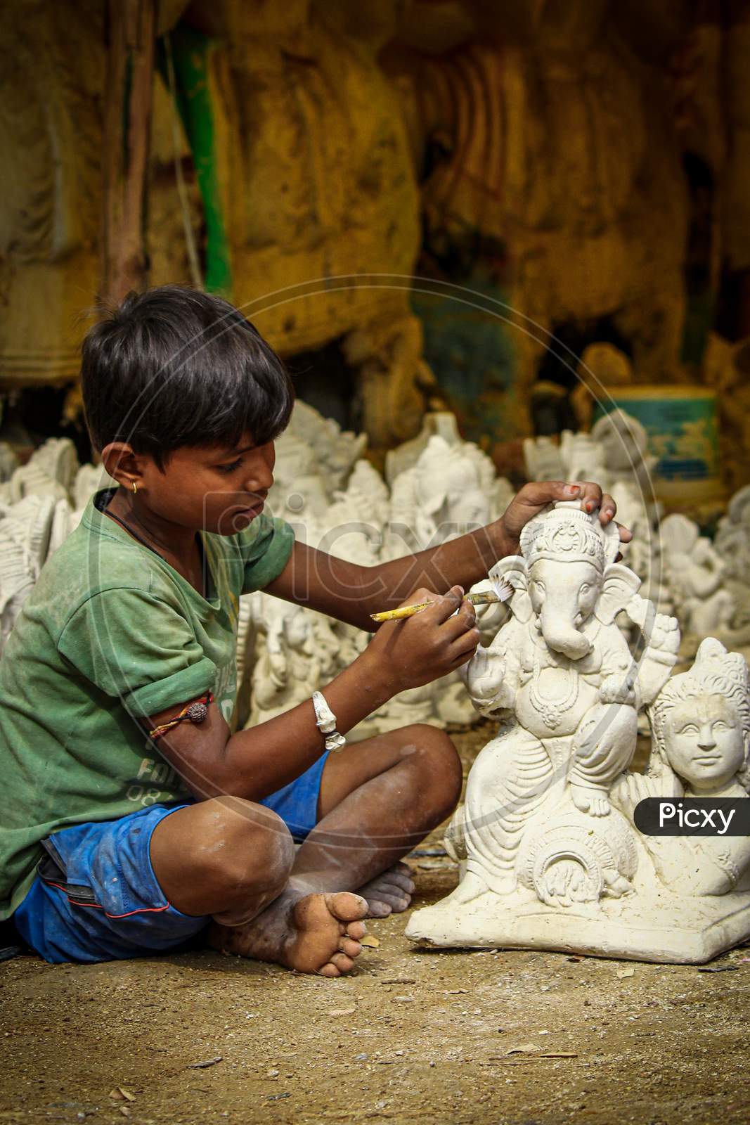 Small kid painting and sculpting ganesh idol