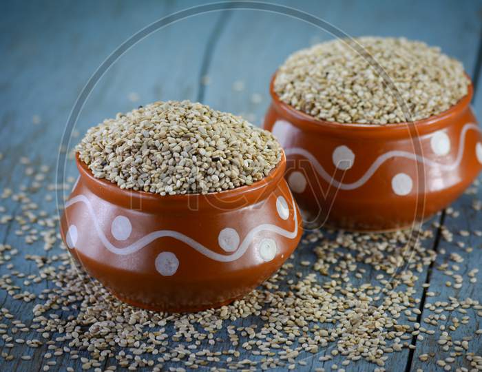 Sesame seeds in clay pot on wooden background