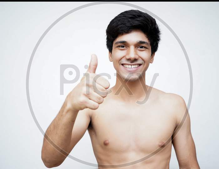 Close up of young guy 20s posing isolated on pastel white wall background studio portrait. People sincere emotions lifestyle concept. Mock up copy space. Showing thumbs up.