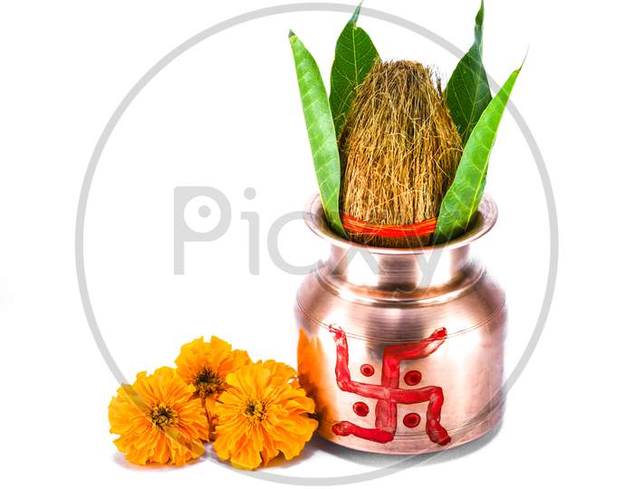 Copper kalash with coconut, mango leaf, and marigold flower isolated on white background