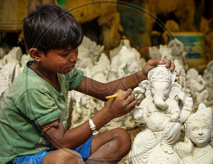 Small kid painting and sculpting ganesh idol