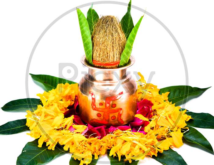 Copper kalash with coconut, mango leaf, and marigold flower isolated on white background