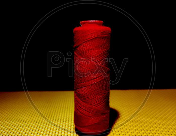 Red Color Sewing Thread With Dark Background.