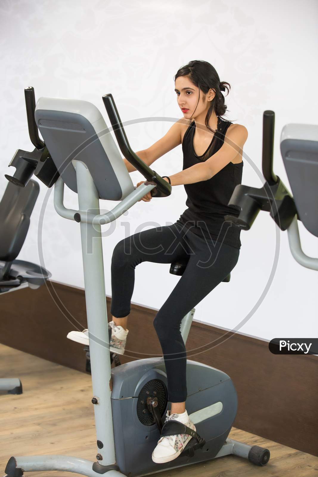 Beautiful Young Girl Working Out On Cycling At Gym