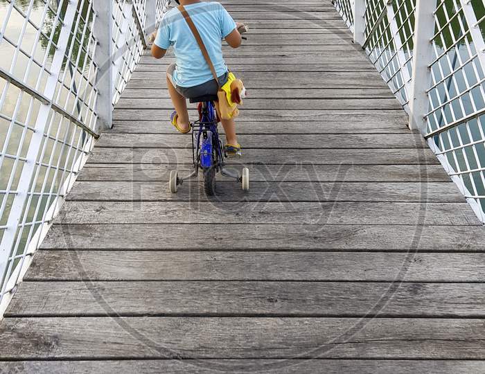 A Boy With Bicycle On A Bridge