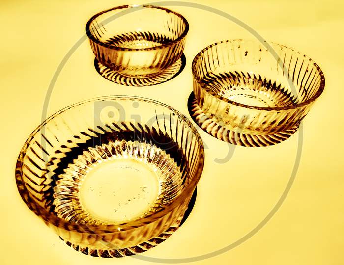 Three elegant charming glass bowls exposed to sunlight isolated in golden background.