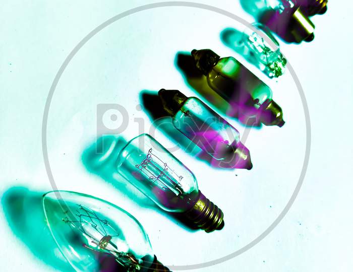 Different shape and sizes DC halogen 12Volt bulbs isolated in cyan & pink shades white background