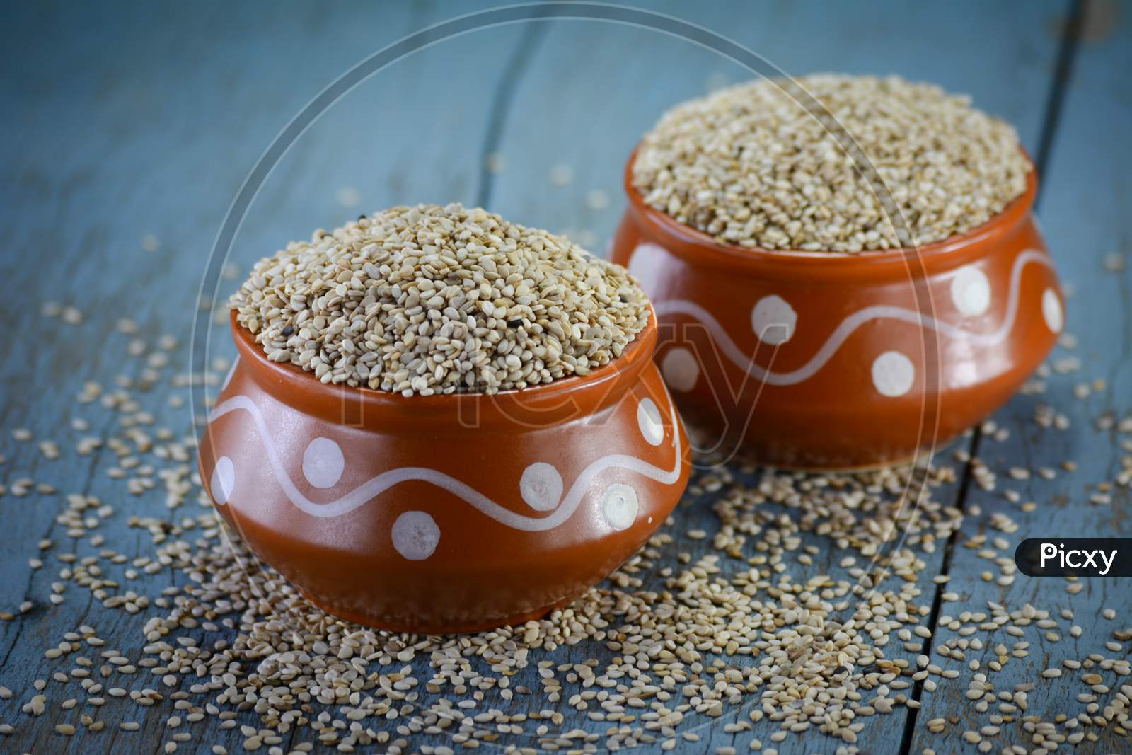 Sesame seeds in clay pot on wooden background