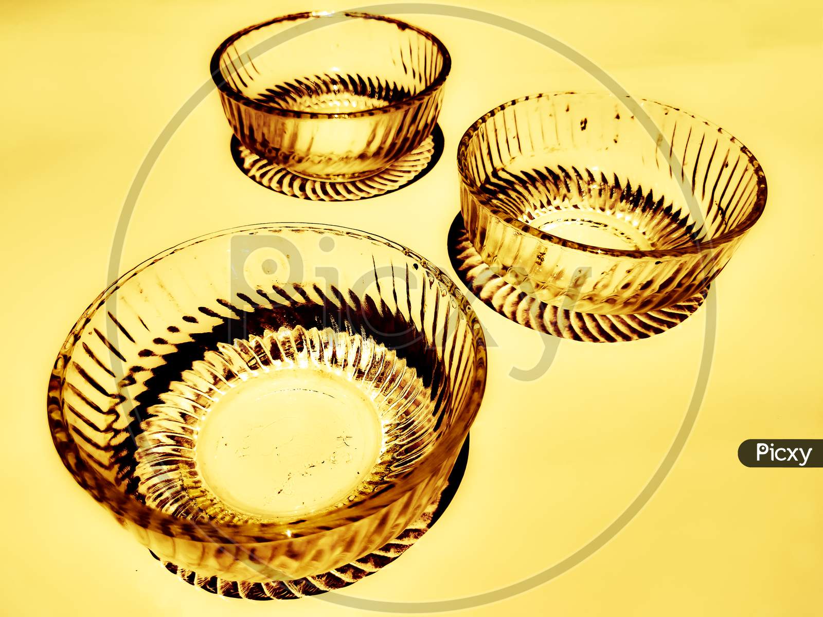 Three elegant charming glass bowls exposed to sunlight isolated in golden background.