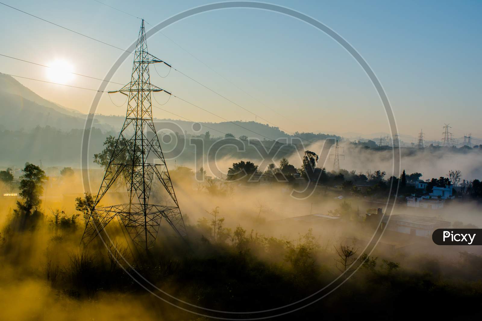 sun rays coming through the trees and electric towers with fog enhancing the light at sunrise, Aerial view