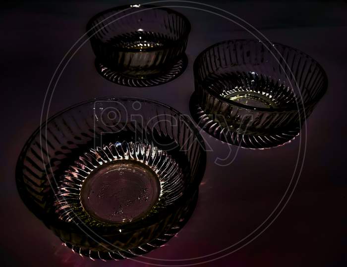 Three elegant charming glass bowls exposed and isolated in dark background.