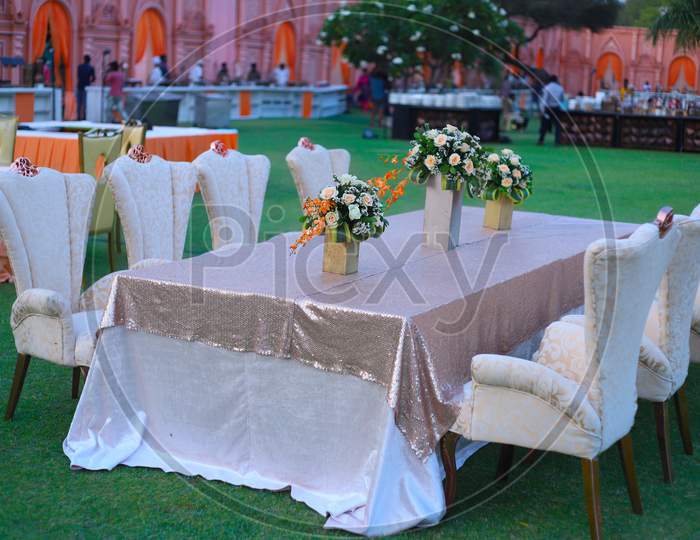 Luxurious Long Dinner Tables And Chairs, Rich Decorated With Flower Pots, Indian Wedding Setup Celebration - Image