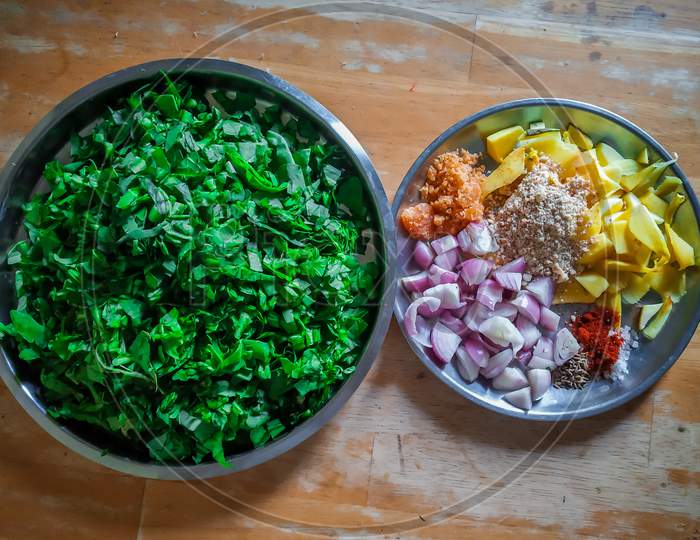 Combined Indian Spices And Ingredients For Making Spinach Curry ( Indian Cuisine ) In A Steel Plate With Wooden Background.
