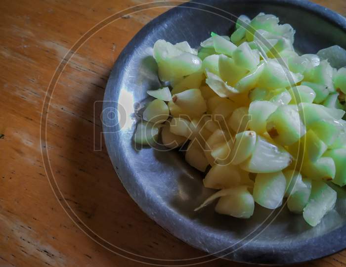 Finely Chopped Garlic In A Steel With Wooden Background.