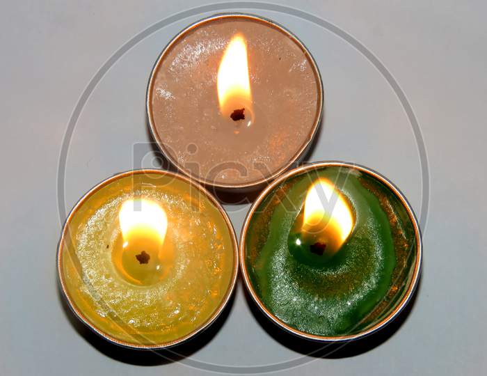 Candles on a white background,Three Beautiful Temple Candles Yellow,Green and white Candles. isolated Burning Candles On a White Background.