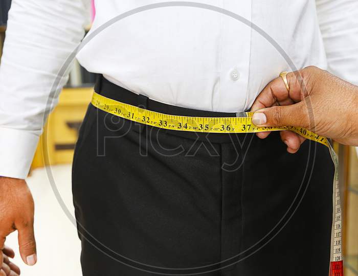 Closeup Of Tailor Taking Measurements Of Man Waist With A Measuring Tape