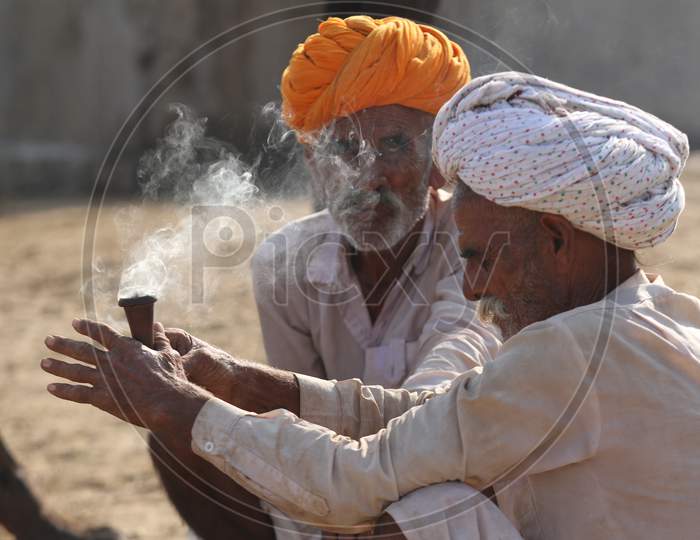 A Rajasthani Camel Trader Smoking Ganja or Marijuana Or Weed At Pushkar Camel Fair, Pushkar