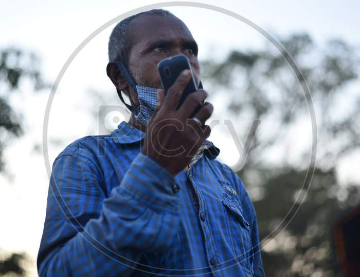 A Migrant worker from Bihar talks over a phone with his family as he waits for clearance to move to his hometown at Telangana-Andhra Pradesh Border , Aswaraopet, Telangana, May 16,2020