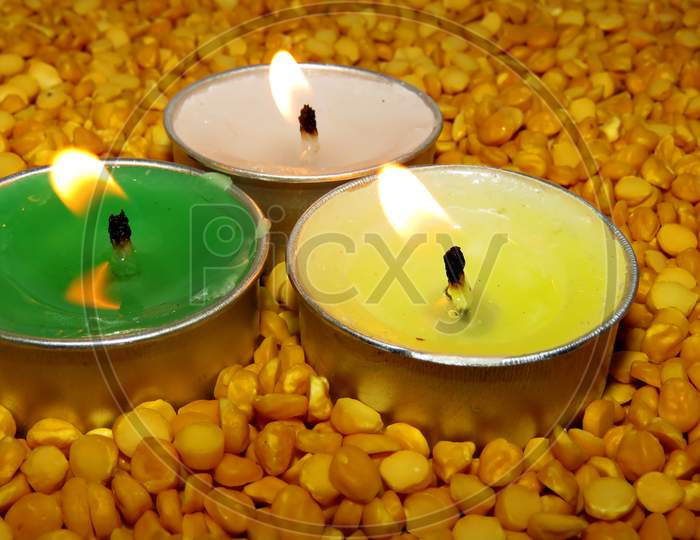Candles on Split pea background,Isolated Green,Yellow And White candles on the seeds,Burning Candles.