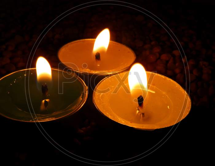 Candles on Split pea background,Isolated Green,Yellow And White candles on the seeds,Burning Candles.isolated temple candles.