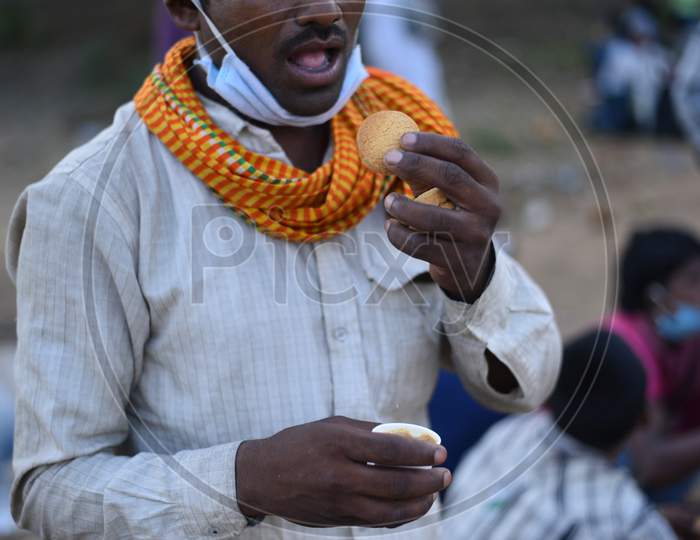 a migrant worker dips a biscuit in tea
