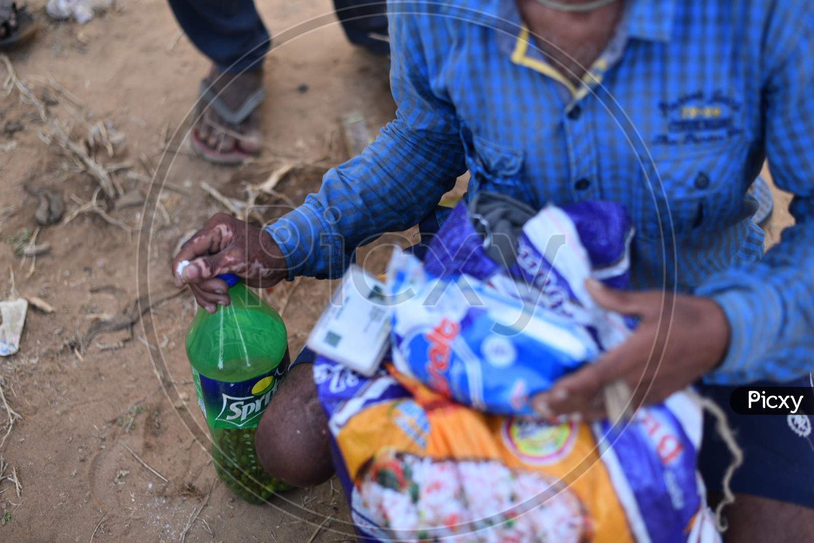 Migrant workers from Bihar eat (Black Gram) Chana as they wait at the Telangana-Andhra Pradesh Border to get permission to cross the border, Aswaraopet, May 16,2020