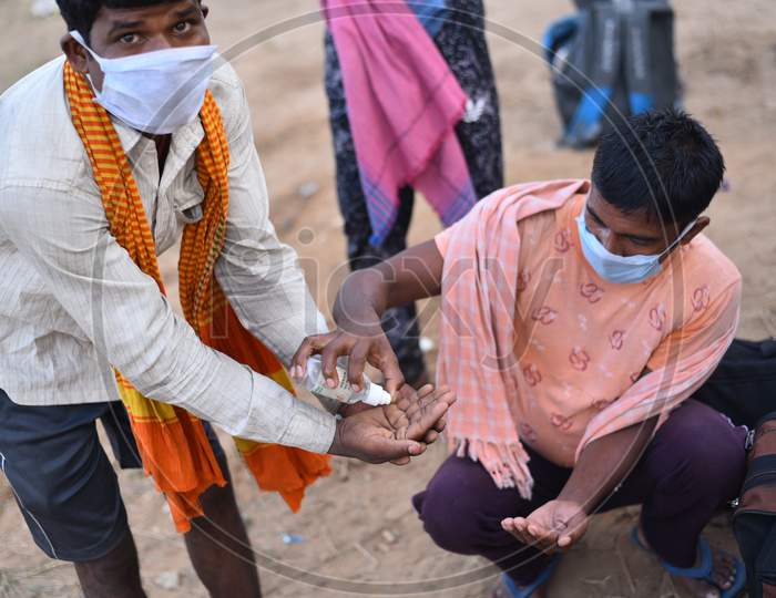 Migrant workers sanitize their hands as they wait at TS-AP Border to get a permission letter to travel across states to reach their hometown in Bihar, May 16,2020, Aswaraopet, Telangana